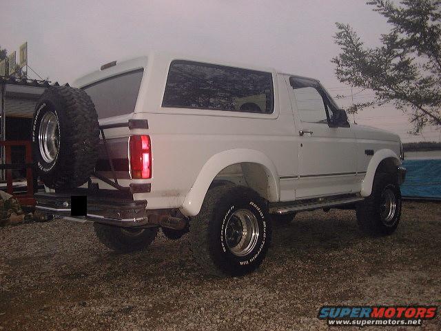 White 1994 Ford Bronco parked outside, rear view with spare tire mounted on the back